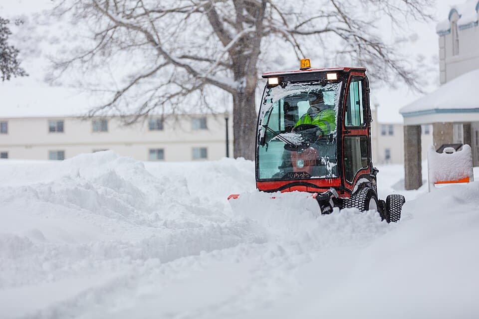 Mitarbeiter räumt nach Schneefall einen Gehweg frei